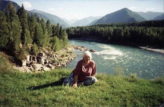 Margaret West sitting in front of a river and mountains in Russia